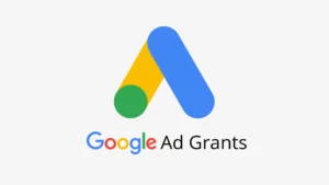 12 mythes sur Google Ad Grants. Main d’une personne manipulant des cubes formant le mot "MYTHS" posés sur un livre, illustrant la déconstruction des idées reçues sur les associations et le numérique.